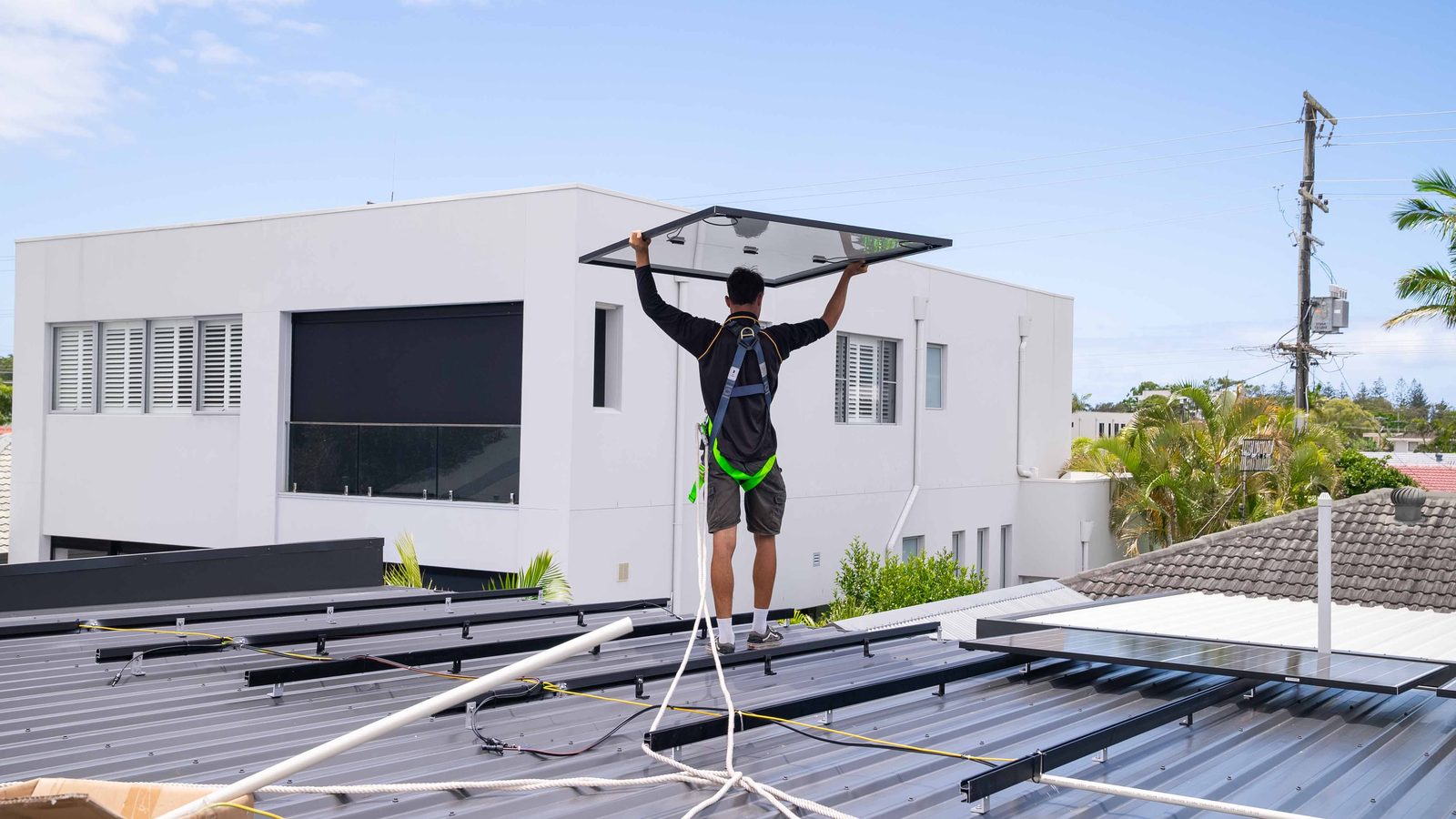 Vivid Electrical installer placing a solar panel on a Gold Coast roof