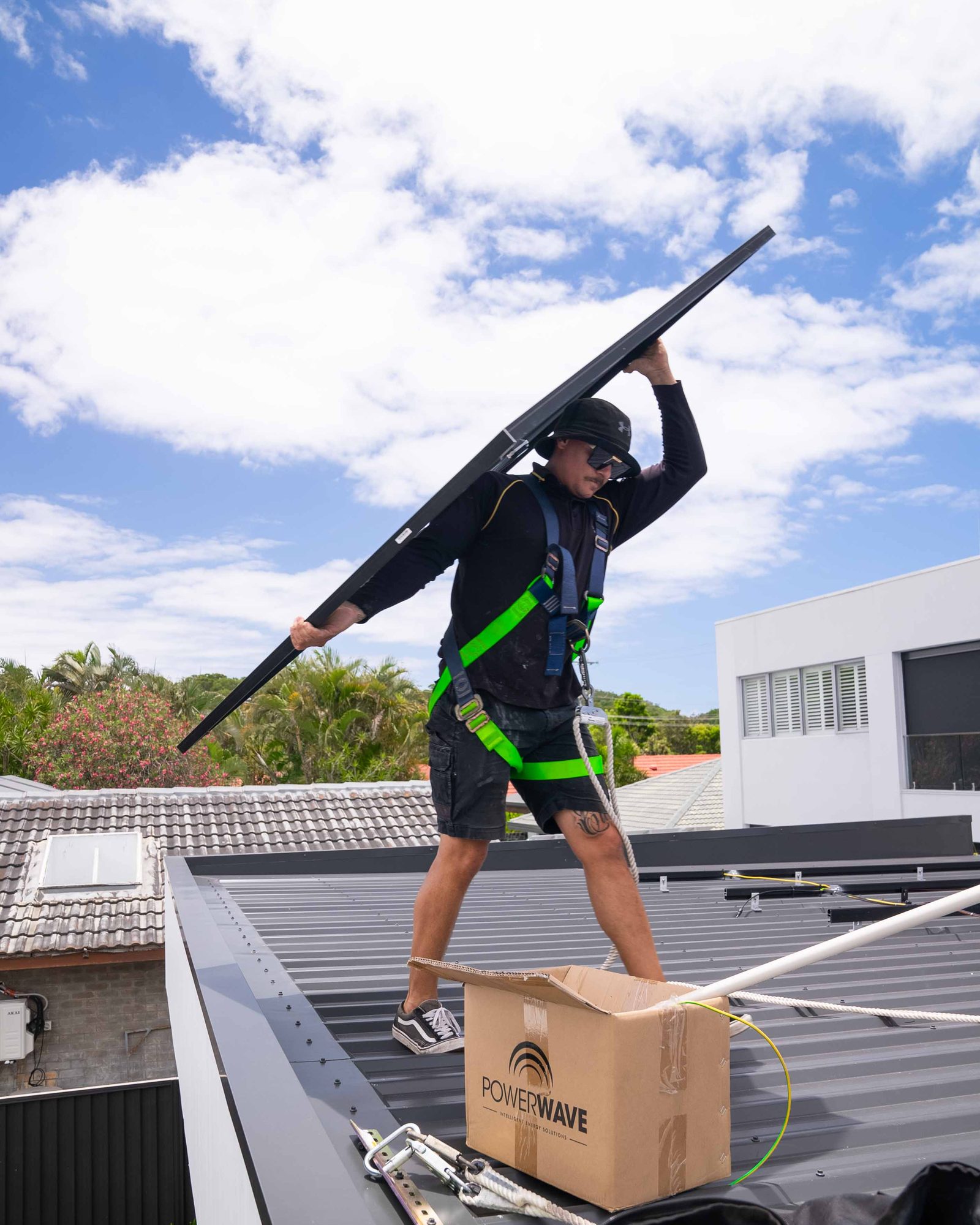 Vivid installer carrying a panel across a roof, harnessed